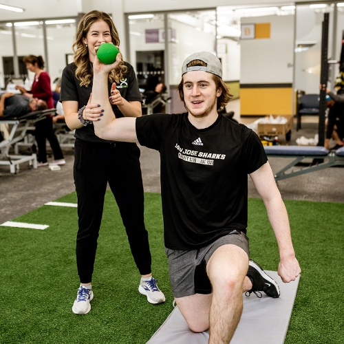 Physiotherapist coaching a patient through a resistance-band shoulder exercise